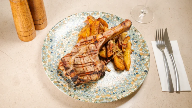 Cotlet de porc cu os & cartofi țărănești – cotlet de porc, cartofi, ulei de floarea soarelui, ceapă. Preparat servit la Restaurant Intim din Focșani