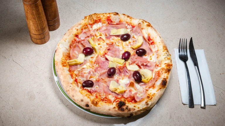 Pizza Capriciosa – aluat dospit 24h, sos de roșii, mozzarella, prosciutto cotto. Preparat servit la Restaurant Intim din Focșani