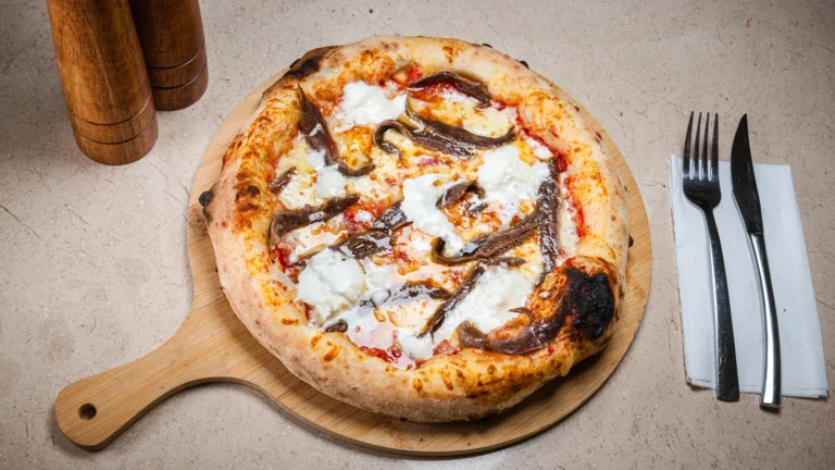 Pizza Napoli – aluat dospit 24h, sos de roșii, mozzarella, anchois. Preparat servit la Restaurant Intim din Focșani