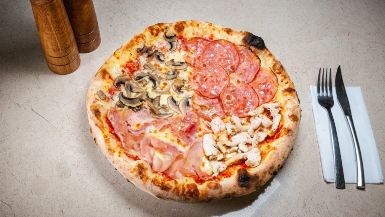 Pizza Quattro Stagioni – aluat dospit 24h, sos de roșii, mozzarella, salam. Preparat servit la Restaurant Intim din Focșani