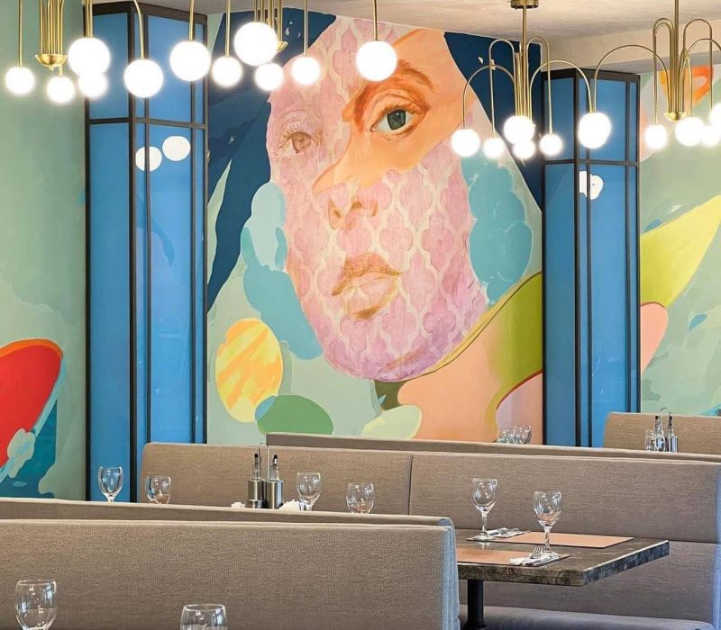 Pictură murală colorată și corpuri de iluminat suspendate în sala Restaurantului Intim